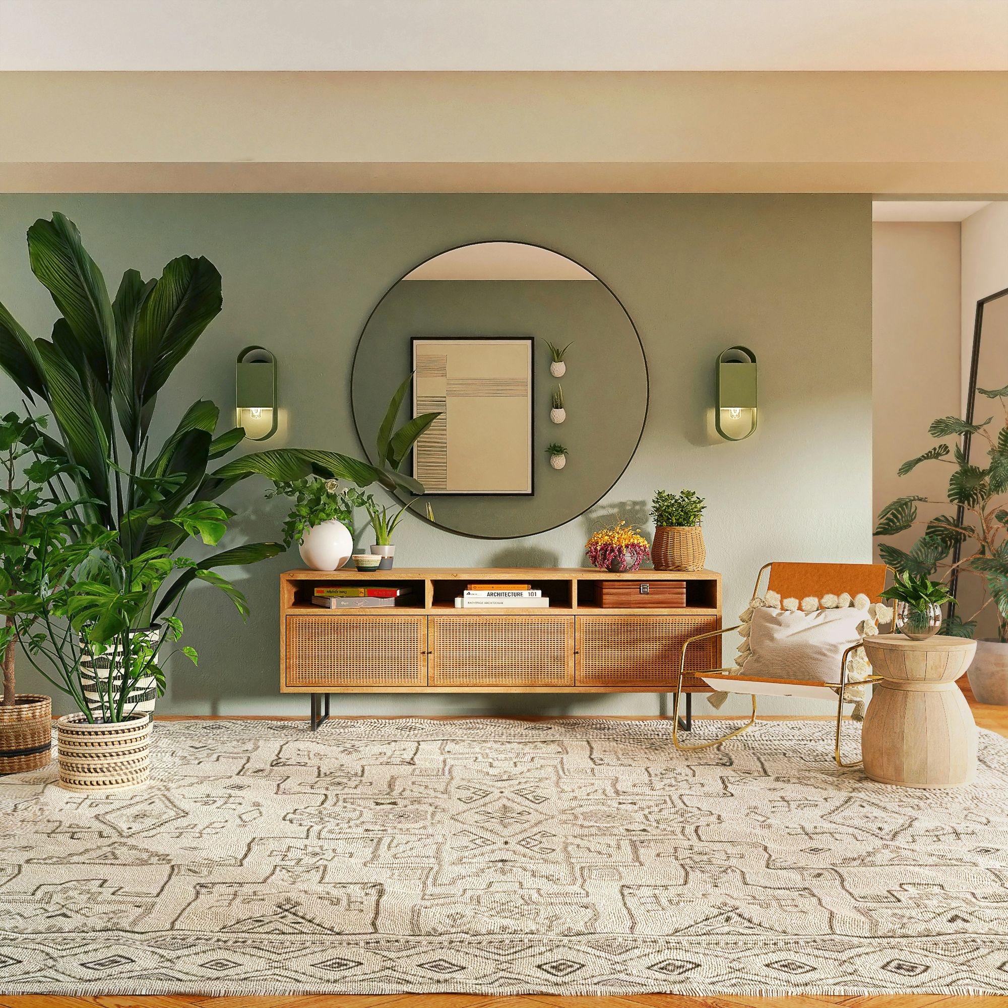 Rattan sideboard styled with plants under a round mirror on a sage wall