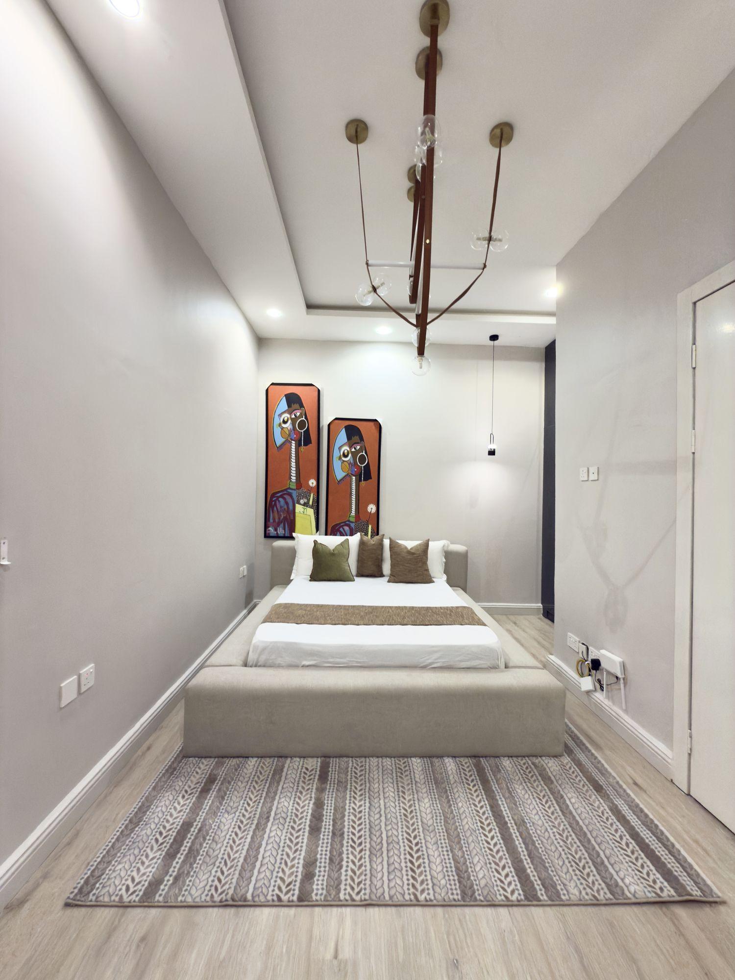 Guest bedroom with paired portrait artworks and a suspended glass globe light