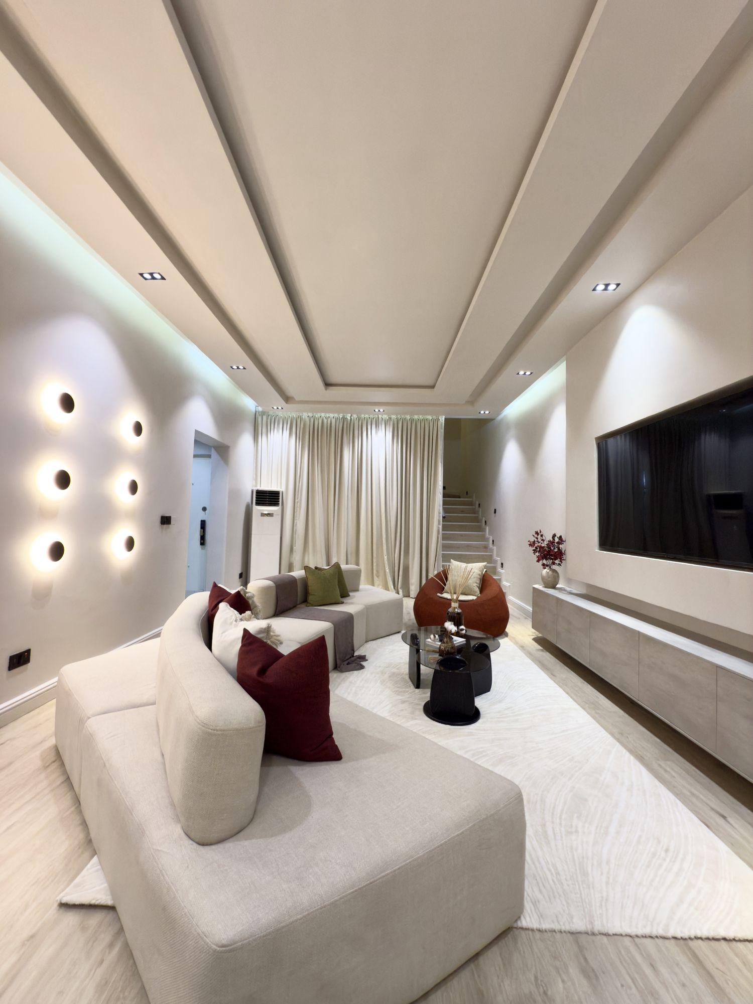 Lounge wall of glowing circular sconces beside curved sofas with wine toned cushions