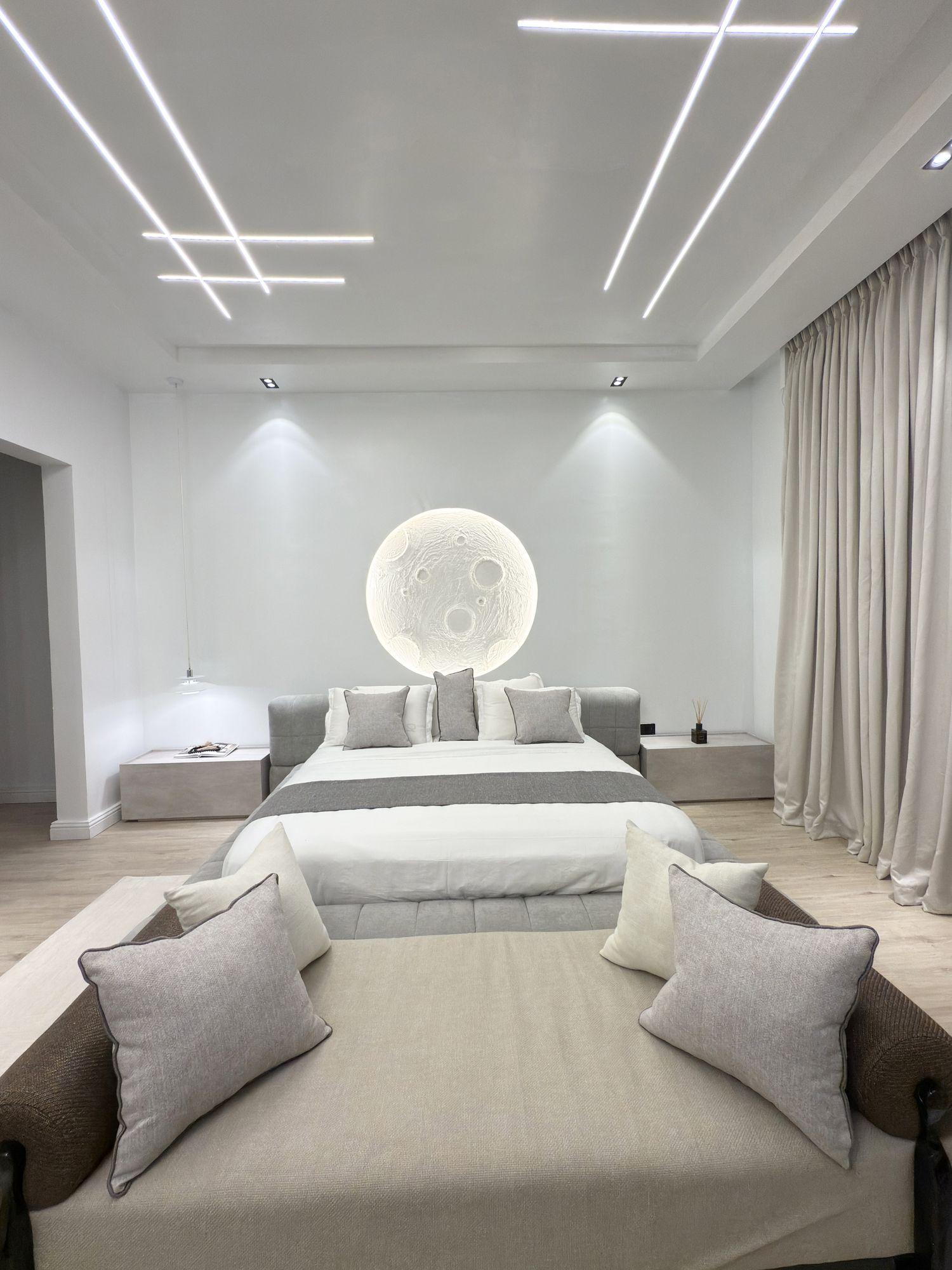Master bedroom with an illuminated moon relief above the bed and linear ceiling lights