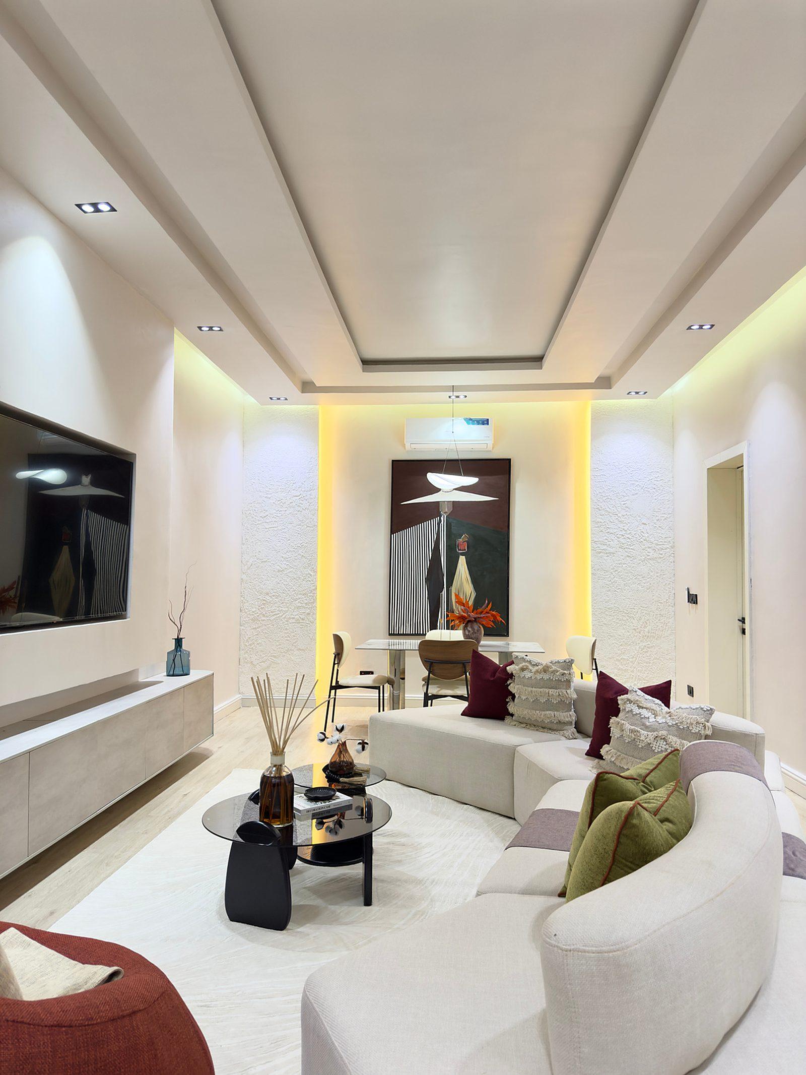 Eclectic apartment living room with a curved sofa, cove lighting and layered cushions