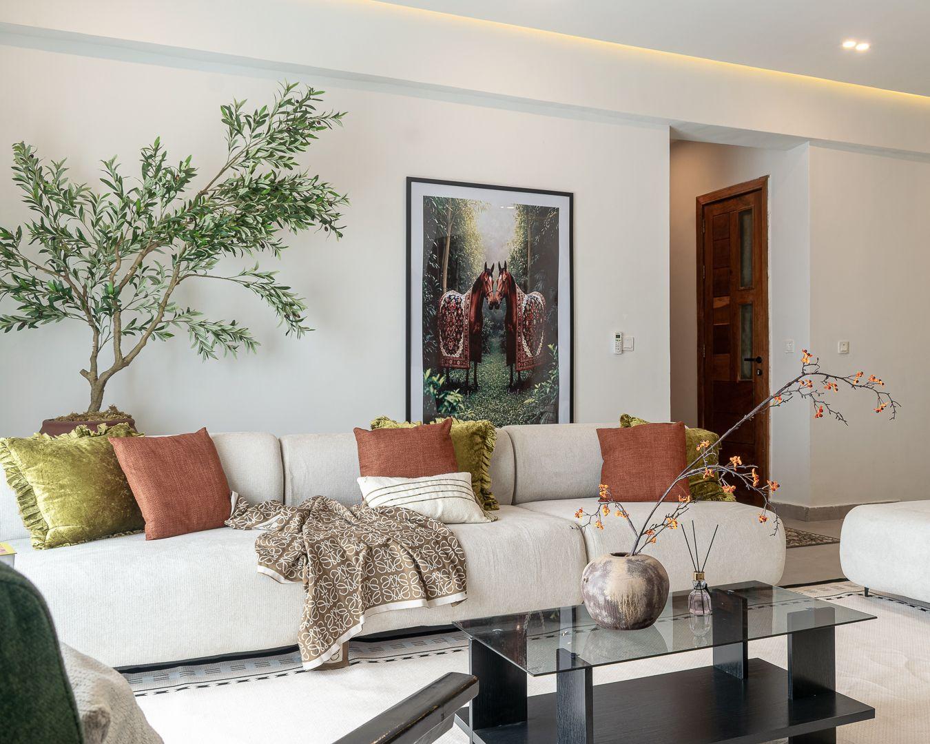 Living room with the framed horses artwork behind a styled cream sofa